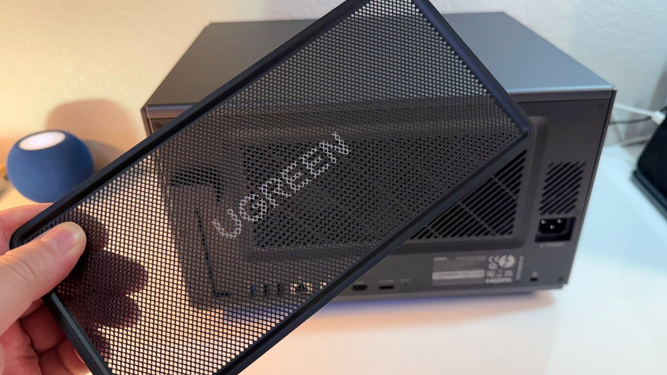 UGREEN iDX6011 Pro magnetic dust filter being held in front of the rear panel